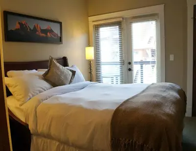 a bedroom with a large white bed with a window at Gracie's Place Business license 11787 in Canmore