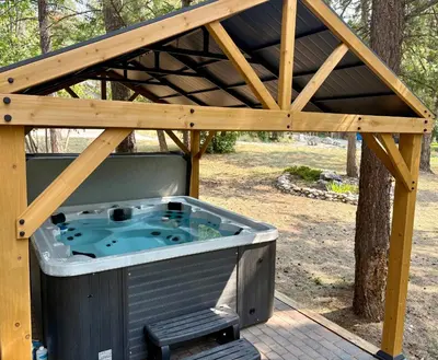 a hot tub under a wooden pergola at Verde Vista - Steam Shower - Theatre - Ping-Pong in Fairmont Hot Springs