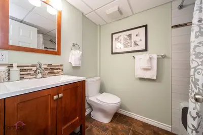a bathroom with a toilet and a sink and a mirror at Stylish Euro Vibes Home, Small Gym, AC, Yard, Office in Edmonton