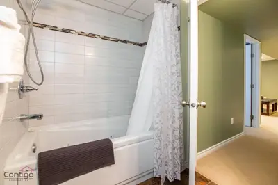 a bath tub with a shower curtain in a bathroom at Stylish Euro Vibes Home, Small Gym, AC, Yard, Office in Edmonton