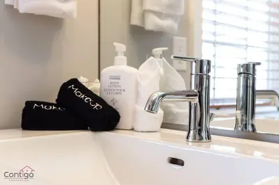 a bathroom sink with a bottle of soap and a mirror at Stylish Euro Vibes Home, Small Gym, AC, Yard, Office in Edmonton