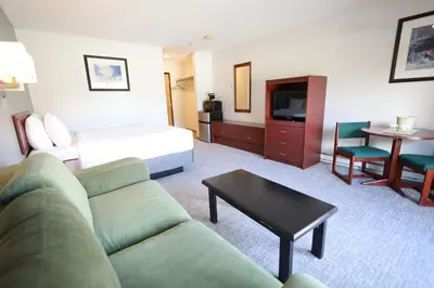a hotel room with a couch and a bed and a table at Glacier Mountain Lodge in Blue River