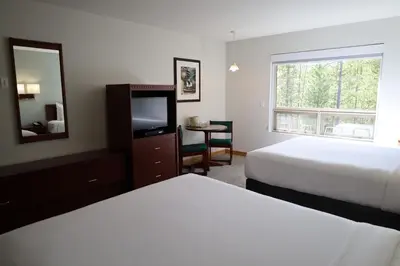 a hotel room with two beds and a television at Glacier Mountain Lodge in Blue River