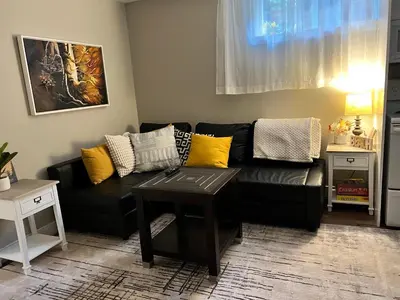 a living room with a black couch with yellow pillows at Yellow Door Suite in Campbell River
