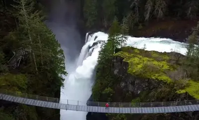 a man on a bridge over a waterfall at Yellow Door Suite in Campbell River