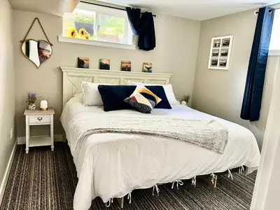 a bedroom with a bed with a white comforter and a window at Yellow Door Suite in Campbell River