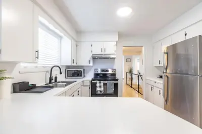 a kitchen with white cabinets and a stainless steel refrigerator at Beautiful Vancouver Special Home in Vancouver