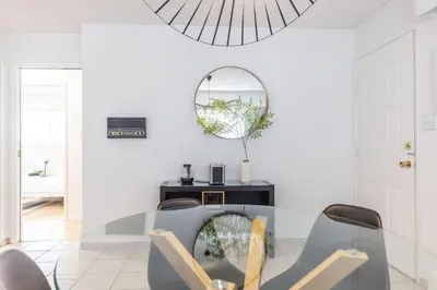 a dining room with a glass table and a mirror at Beautiful Vancouver Special Home in Vancouver