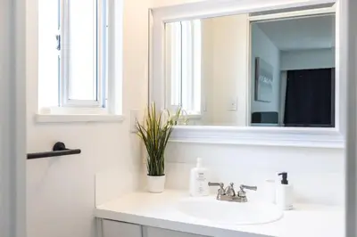 a white bathroom with a sink and a mirror at Beautiful Vancouver Special Home in Vancouver
