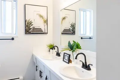 a bathroom with two sinks and two mirrors at Beautiful Vancouver Special Home in Vancouver