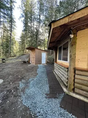 a log cabin with a driveway next to a building at Cabin in the woods @ Cultus Lake in Chilliwack