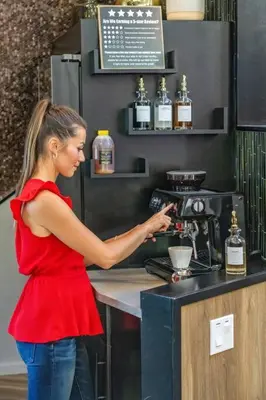 a woman in a red shirt standing at a coffee machine at Dome House YYC, Iconic, Luxury, Backyard Oasis in Calgary