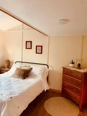 a bedroom with a white bed and a wooden dresser at Ski-In Chalet: Private Hot tub, Bonus Bunk House in Fernie