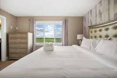a bedroom with a large white bed and a window at Large Detached Near Anthony Henday in Albany with 2 Living Rooms, Netflix, Office Space, AC, Perfect for Families, Sleeps 13 in Edmonton