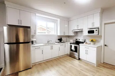 a kitchen with white cabinets and a stainless steel refrigerator at Gorgeous 2 Bedrooms Suite Private entrance with patio-Free Parking in Maple Ridge District Municipality