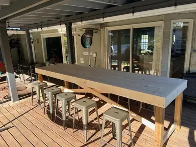 a large wooden table and stools on a deck at Family, Pet Friendly Sechelt Waterfront Home, Beach Access, Sleeps 14 in Sechelt