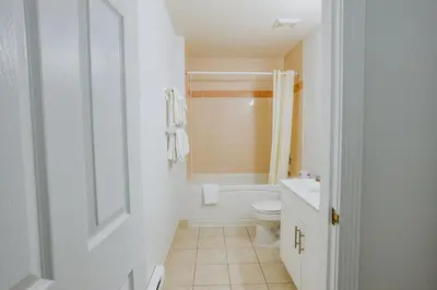 a white bathroom with a toilet and a sink at Western Budget Plus Mosaic Suites in Red Deer
