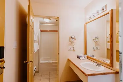 a bathroom with a sink and a mirror at Western Budget Plus Mosaic Suites in Red Deer