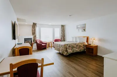 a hotel room with a bed and a desk at Western Budget Plus Mosaic Suites in Red Deer