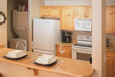 a kitchen with a table with two wine glasses on it at Crystal Forest #51 condo in Sun Peaks