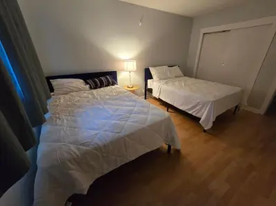 a bedroom with two beds and a lamp in it at 3 Bedroom Home away from Home in Calgary