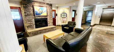 a living room with leather furniture and a fireplace at Park Hill Inn & Suite in Red Deer