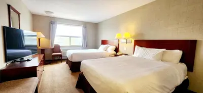 a hotel room with two beds and a flat screen tv at Park Hill Inn & Suite in Red Deer