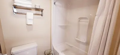 a white bathroom with a shower and a toilet at Park Hill Inn & Suite in Red Deer