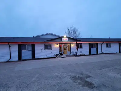 a white building with a neon sign on it at GRIZZLY MOTEL in Swan Hills