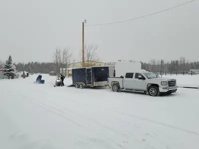 a white truck pulling a trailer in the snow at GRIZZLY MOTEL in Swan Hills