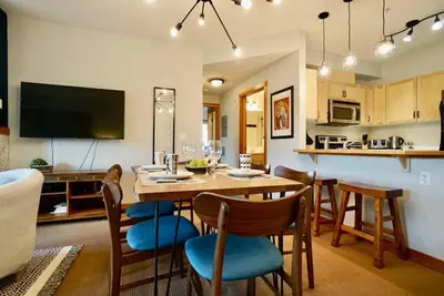 a kitchen and dining room with a table and chairs at L202 - A Relaxed Vacation- 2BD+2BT, Heated Pool, Hot tubs, Gym, AC, Parkade in Canmore