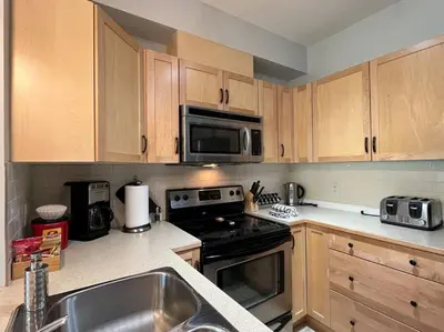 a kitchen with wooden cabinets and a stove and microwave at L202 - A Relaxed Vacation- 2BD+2BT, Heated Pool, Hot tubs, Gym, AC, Parkade in Canmore