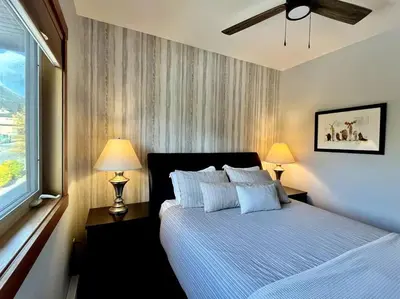 a bedroom with a bed with two lamps and a window at L202 - A Relaxed Vacation- 2BD+2BT, Heated Pool, Hot tubs, Gym, AC, Parkade in Canmore