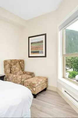 a bedroom with a chair and a bed and a window at Lakeview Splendor- 7BR Penthouse Bliss Combo unit in Harrison Hot Springs