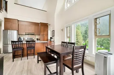 a kitchen with a wooden table and chairs and a counter at Lakeview Splendor- 7BR Penthouse Bliss Combo unit in Harrison Hot Springs
