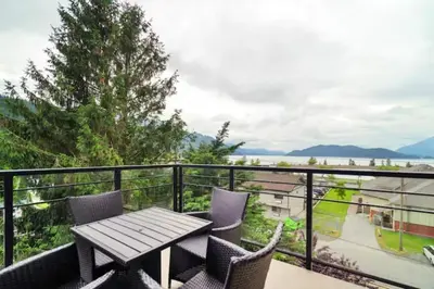 a patio with a table and chairs on a balcony at Lakeview Splendor- 7BR Penthouse Bliss Combo unit in Harrison Hot Springs