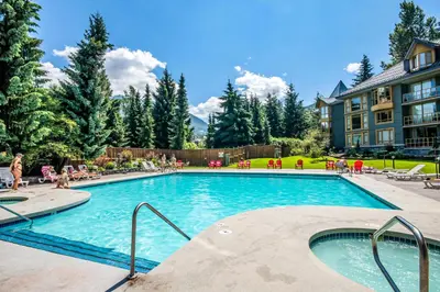 a swimming pool at a resort with people sitting around it at Cascade Lodge in Whistler