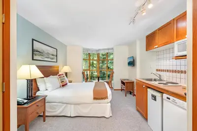 a bedroom with a large bed and a kitchen at Cascade Lodge in Whistler