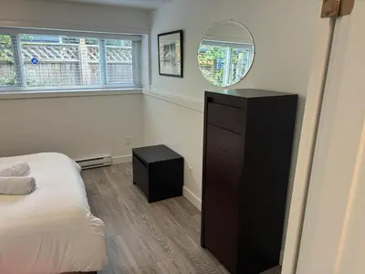 a bedroom with a black dresser and a mirror at Large 2 bedroom private suite ! in North Vancouver