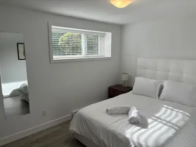 a white bedroom with a bed and a window at Large 2 bedroom private suite ! in North Vancouver