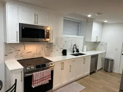 a kitchen with white cabinets and a sink and a microwave at Guest suite in Southwest Calgary in Calgary