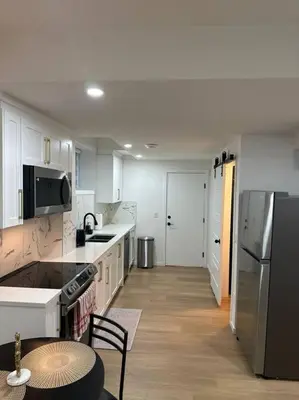 a kitchen with white cabinets and a refrigerator and a table at Guest suite in Southwest Calgary in Calgary