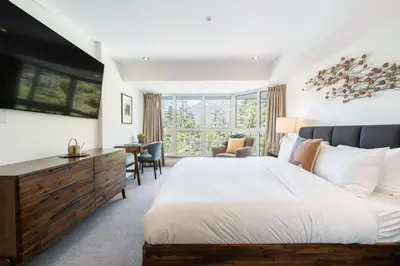 a bedroom with a large bed and a desk at Le Chamois by Outpost Whistler in Whistler