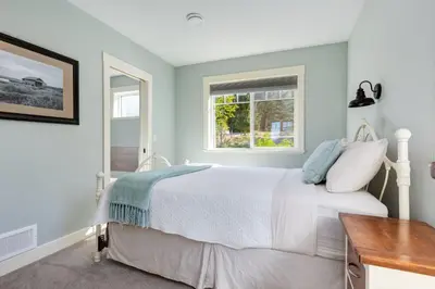 a bedroom with a white bed and a window at The Nest in Lantzville