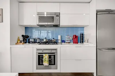 a white kitchen with a stove and a microwave at Central Luxury Apartment with Best City Views! in Vancouver