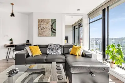 a living room with a black leather couch and large windows at Central Luxury Apartment with Best City Views! in Vancouver