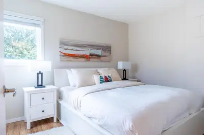 a white bedroom with a bed and a window at Ski nest 5m to Creekside Gondola in Whistler