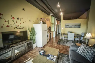 a living room with a couch and a table and a refrigerator at 2 Full Beds, Rogers Place Downtown Central, Memorable 1 Bedroom Condo in Edmonton
