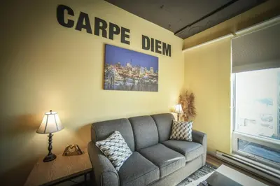 a living room with a couch and a sign on the wall at 2 Full Beds, Rogers Place Downtown Central, Memorable 1 Bedroom Condo in Edmonton