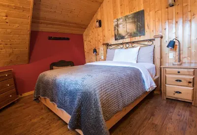 a bedroom with a bed and a wooden wall at Cabins West in Ucluelet